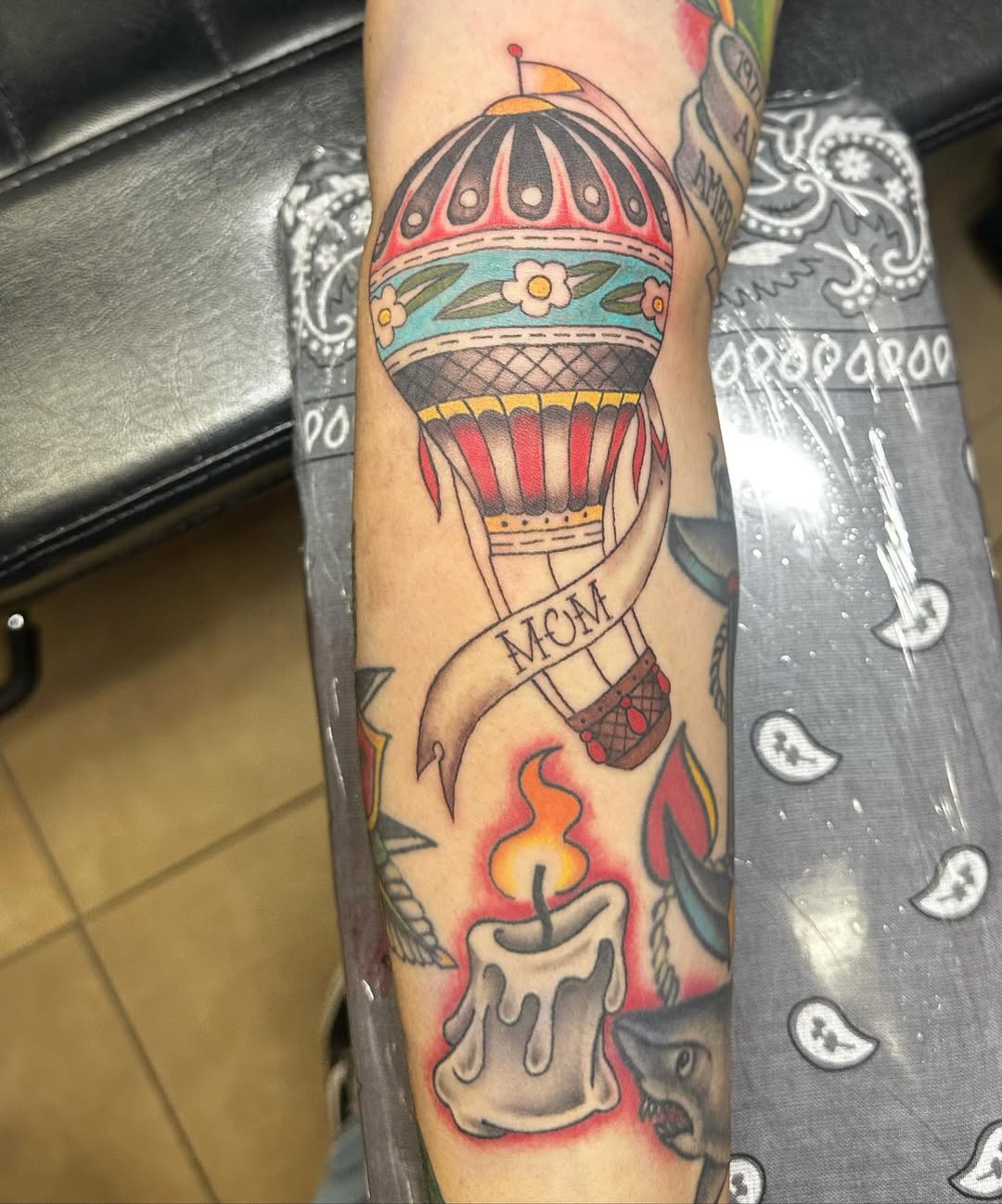 Traditional hot air balloon with 'MOM' banner and candle tattoo